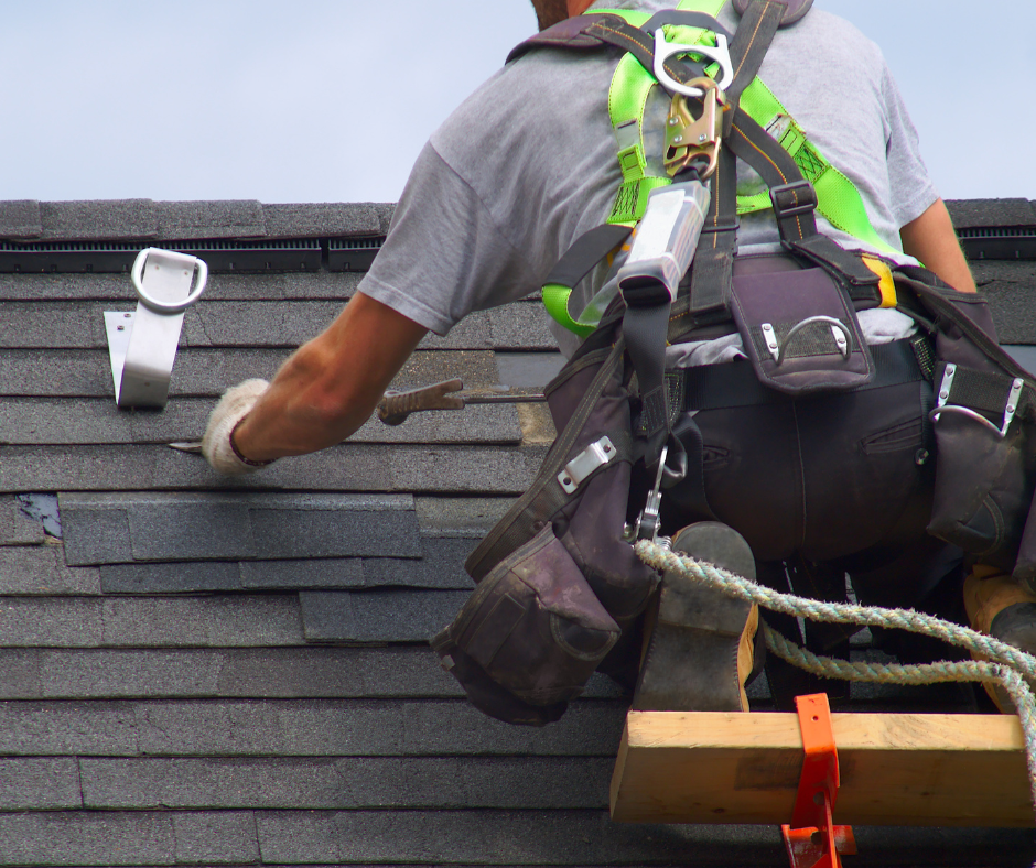 Roofer working on an asphalt shingle roof with safety equipment
